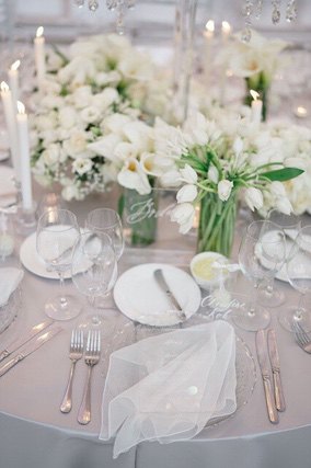 White flowers, candles, plates and napkin on round table
