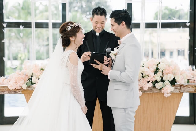 Bride, Groom and priest laughing during wedding ceremony
