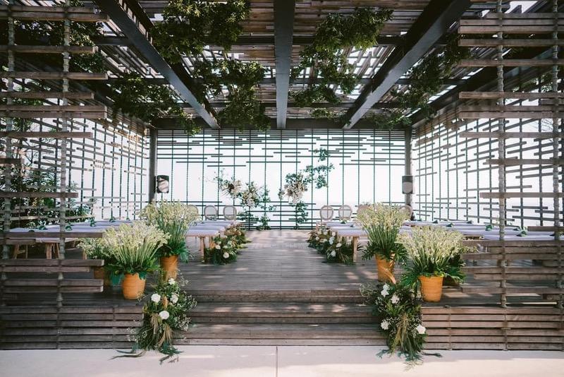  Wedding ceremony setup inside the cabana at Alila Villas Uluwatu, adorned with lush greenery, wooden accents, and natural floral arrangements for a rustic, elegant ambiance. 