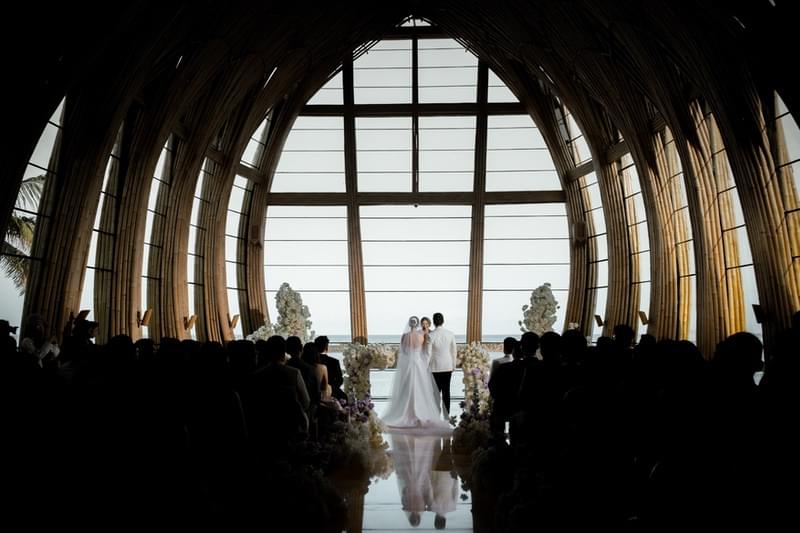  Bride and groom exchanging vows in the stunning bamboo Apurva Chapel, with ocean views at The Apurva Kempinski Nusa Dua 