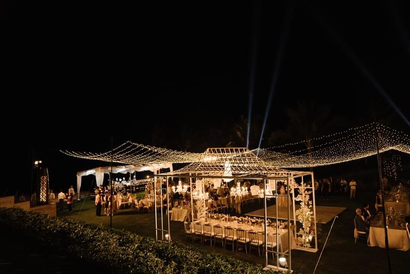  Wedding reception setup under twinkling lights on the front lawn of The Apurva Kempinski front lawn, with elegant dining and guests enjoying the evening celebration 