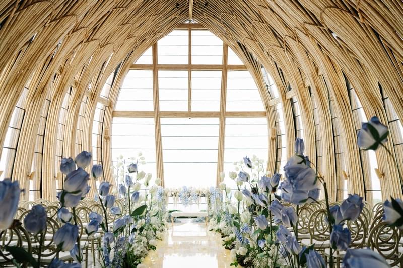  The Apurva Chapel at The Apurva Kempinski Nusa Dua beautifully decorated with blue flowers for a wedding ceremony, offering a stunning view of the ocean through its large windows 