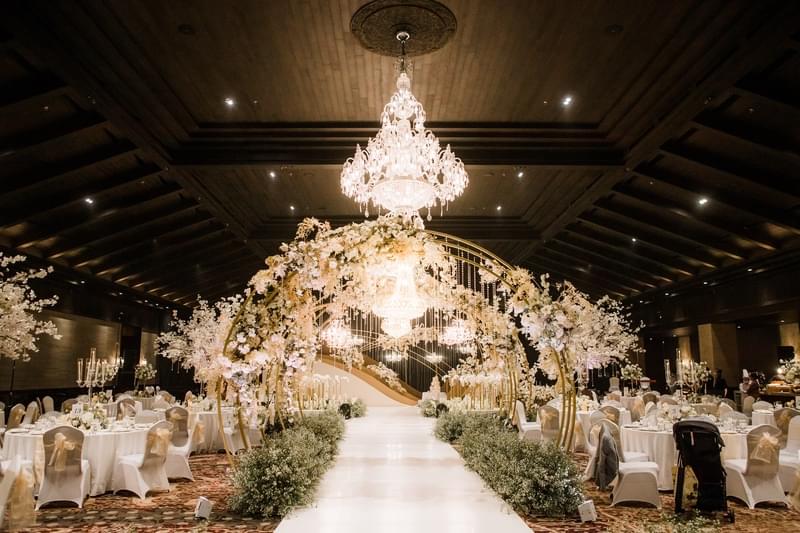  Luxurious wedding setup in the Candi Ballroom at The Apurva Kempinski, featuring opulent chandeliers, floral arches, and elegantly arranged dining tables 