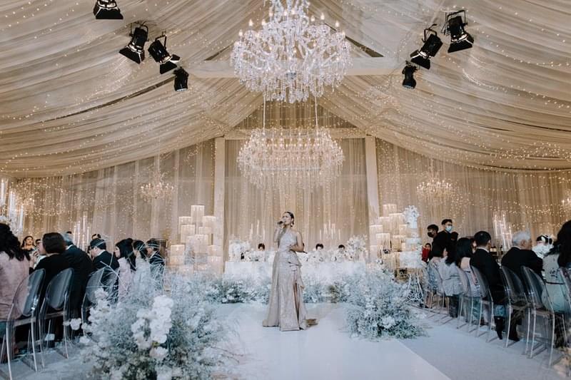  Wedding reception in the Candi Ballroom at The Apurva Kempinski with live singer, grand chandeliers, and luxurious floral decor 