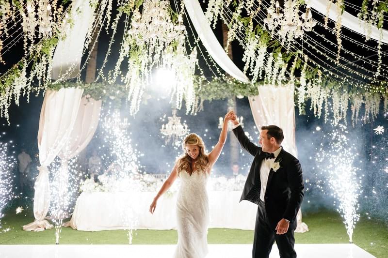  Bride and groom celebrate their first dance surrounded by sparklers under a floral canopy with draped curtains and chandeliers at Khayangan Estat 
