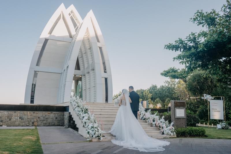  Father and Bride walking up the flower-adorned steps to the Majestic Chapel at The Ritz-Carlton Bali 