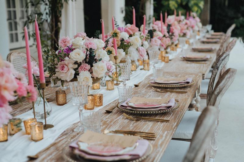 Elegant wedding reception table at Villa Tamarama, with soft pink floral centerpieces, golden candles, and a beautifully set dining arrangement 