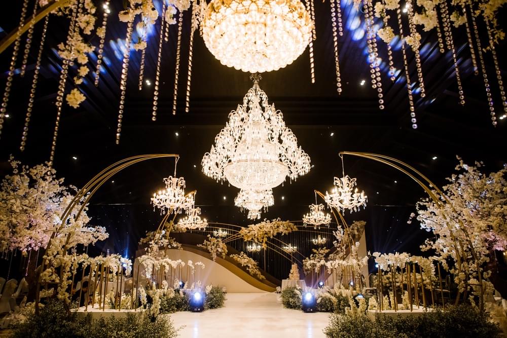 Luxurious wedding reception setup in The Apurva Kempinski’s Candi Ballroom, featuring cascading chandeliers, golden arches, and elegant floral arrangements for a glamorous ambiance.