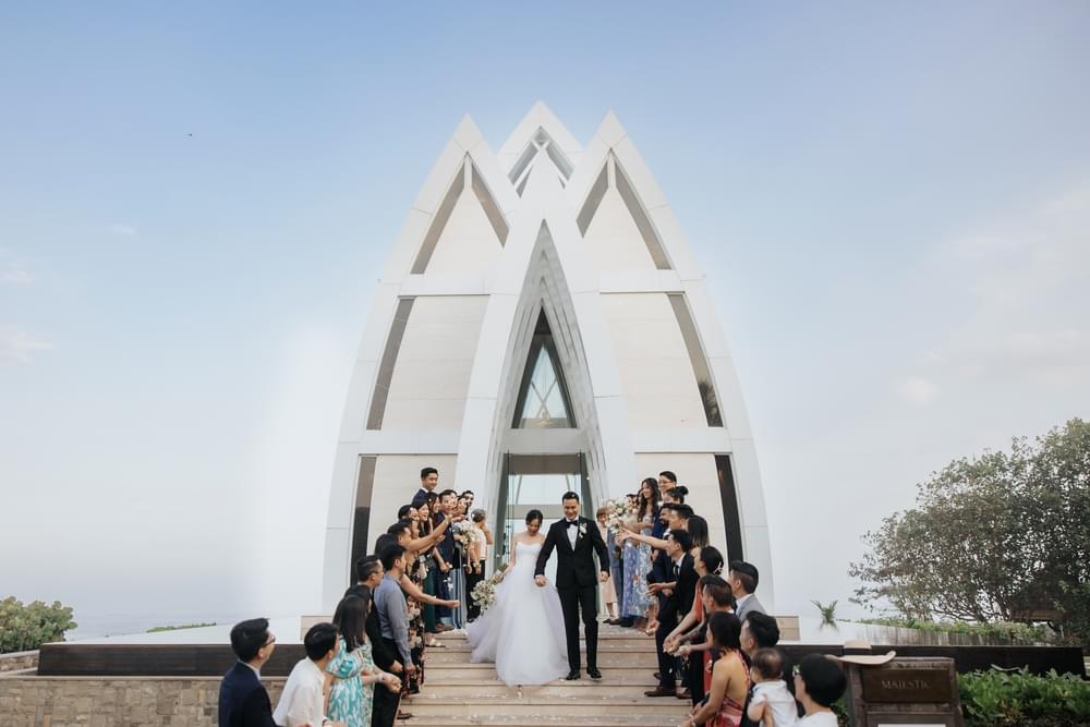 Bride and groom exiting the striking Majestic Chapel at Ritz Carlton Bali, surrounded by friends and family celebrating their union.