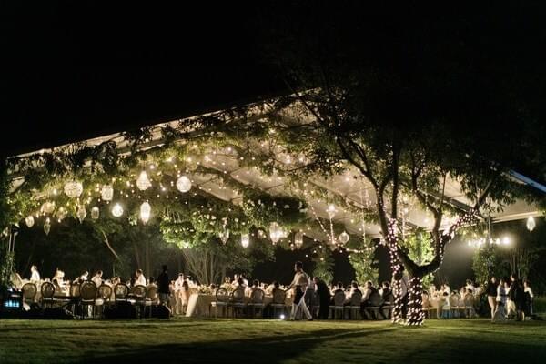 Evening view of an illuminated marquee at Alila Villas Uluwatu, glowing warmly against the night sky and surrounded by lush greenery